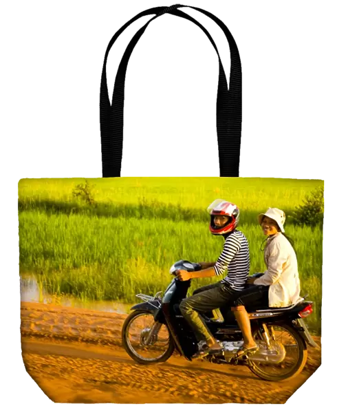 Girls riding along a dirt road in Cambodia