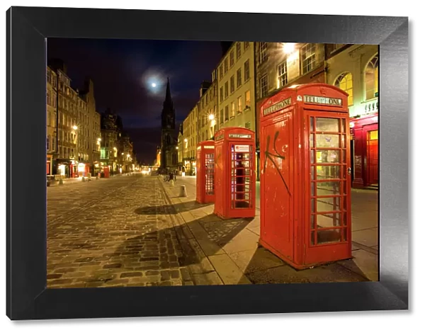 Scotland, Edinburgh, The Royal Mile. Cobbled stone road and traditional red telephone boxes in the High Street, part of the historic Royal Mile in the