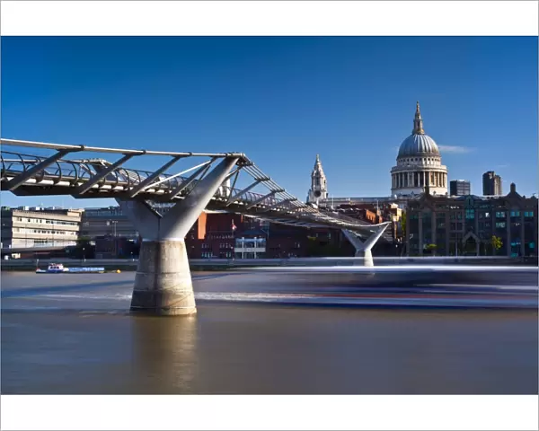 England, London, St Pauls Cathedral. A boat passes below the London Millennium Bridge which links the south bank of the Thames with St Pauls Cathedral and