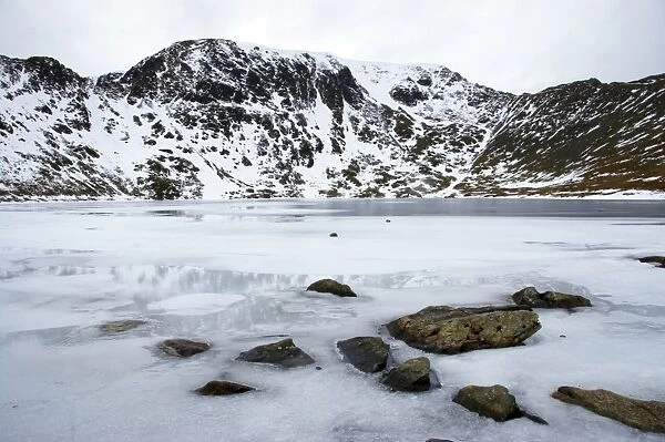 England, Cumbria, Lake District National Park. Rocks and the ice covered expanse of Red Tarn