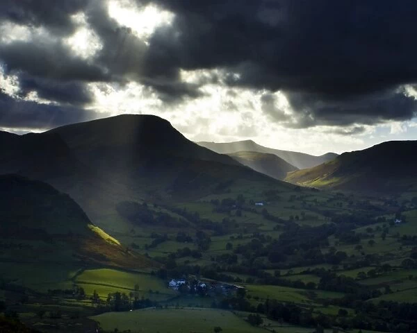 England, Cumbria, Lake District National Park. A shaft of light breaks through storm clouds above the north
