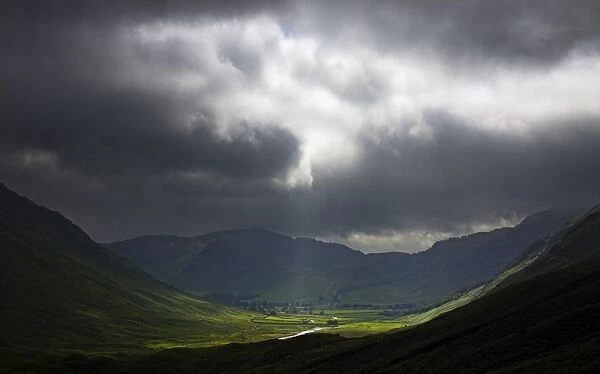 ENGLAND, Cumbria, Lake District National Park. A break in the storm clouds illuminates