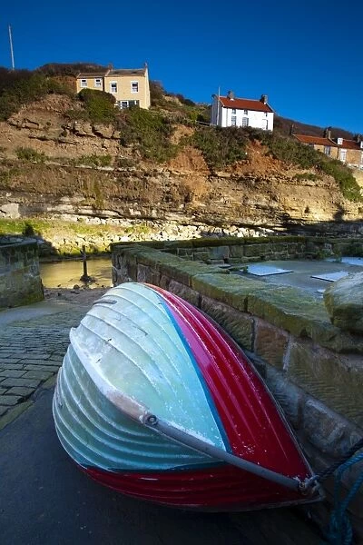 England, North Yorkshire, Staithes. Fishing boat moored near to a river in the old town of Staithes