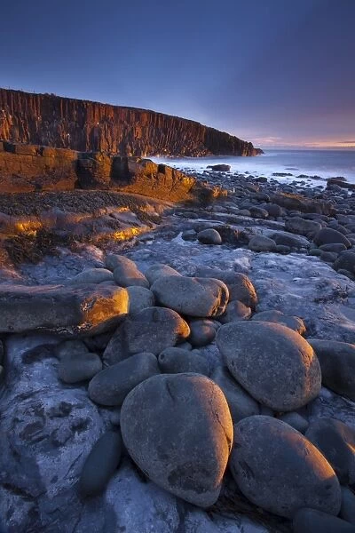 England, Northumberland, Cullernose Point. Dawn light illuminates the rocky shoreline of Cullernose Point, near the village of Craster on the Northumberland