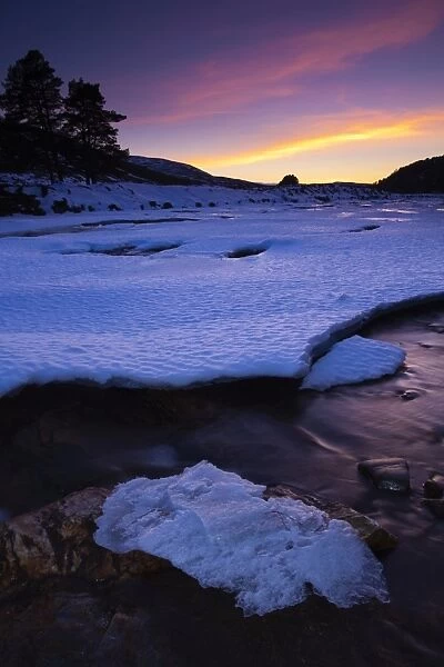 Scotland, Aberdeenshire, Linn of Dee. Pink sunset over the ice covered River Dee near the bridge over the Linn