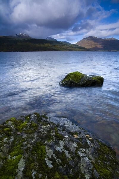 Scotland, Stirling, Loch Lomond and the Trossachs National Park. Moss covered boulders on Loch Lomond with mountains in