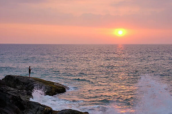 Sri Lanka, Galle District, Ahungalla. Tourist enjoys the sunset whilst fishing at Ahungalla Beach