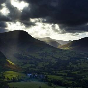 England, Cumbria, Lake District National Park. A shaft of light breaks through storm clouds above the north