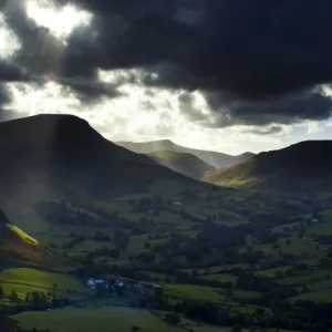 England, Cumbria, Lake District National Park. A shaft of light breaks through storm clouds above the north