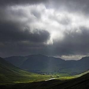 ENGLAND, Cumbria, Lake District National Park. A break in the storm clouds illuminates