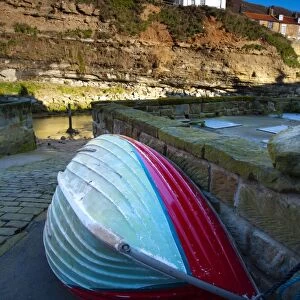 England, North Yorkshire, Staithes. Fishing boat moored near to a river in the old town of Staithes