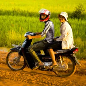 Girls riding along a dirt road in Cambodia