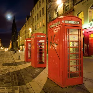 Scotland, Edinburgh, The Royal Mile. Cobbled stone road and traditional red telephone boxes in the High Street, part of the historic Royal Mile in the