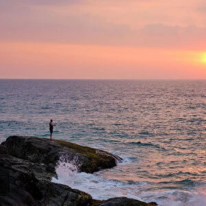 Sri Lanka, Galle District, Ahungalla. Tourist enjoys the sunset whilst fishing at Ahungalla Beach