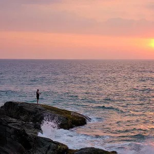 Sri Lanka, Galle District, Ahungalla. Tourist enjoys the sunset whilst fishing at Ahungalla Beach