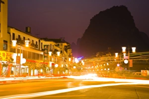 China, Guangxi Zhuang Autonomous Region, Yangshuo City. Busy traffic running through a chinese city at night with a backdop of limestone