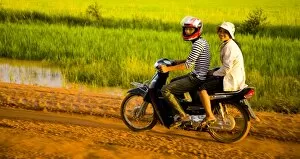 South Collection: Girls riding along a dirt road in Cambodia